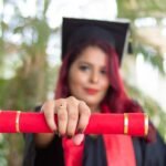 woman in red long sleeve shirt holding red and black academic hat